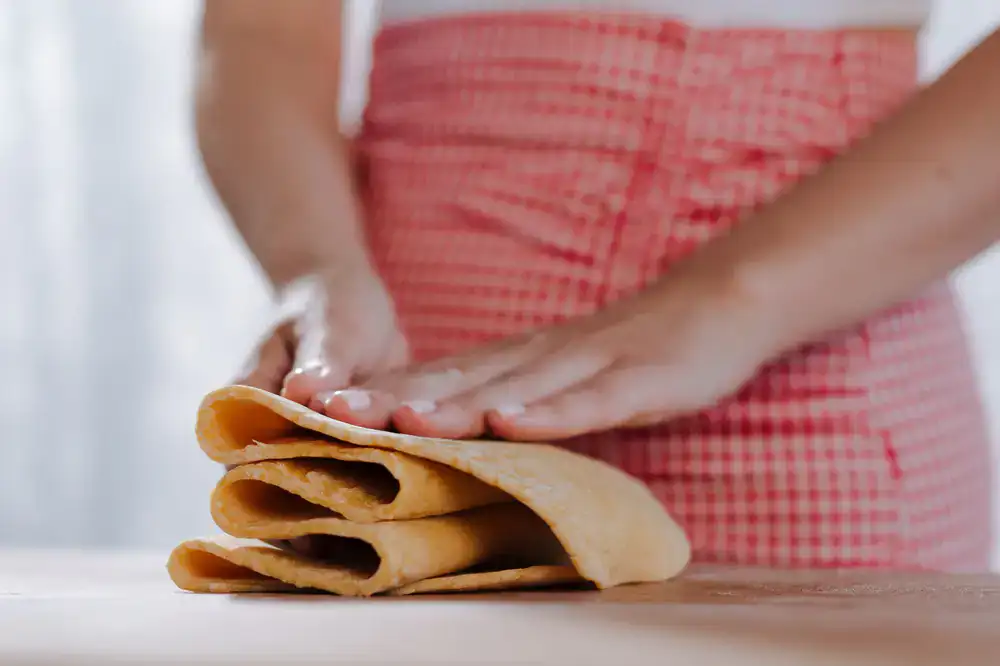 Hands delicately folding fresh pasta dough on a wooden board dusted with semolina