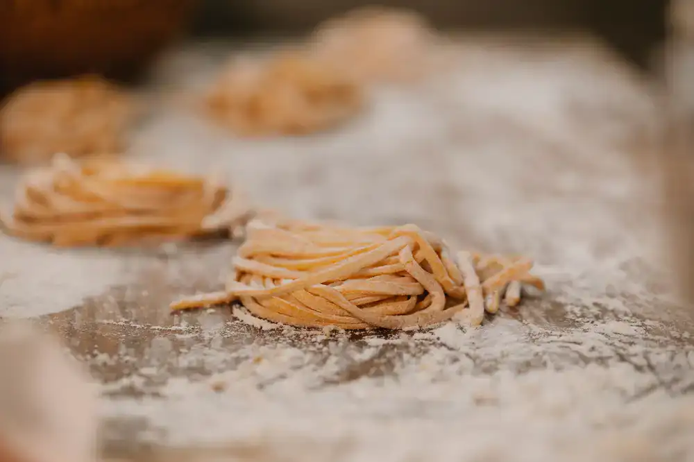 Nests of fresh tagliatelle pasta on a floured surface