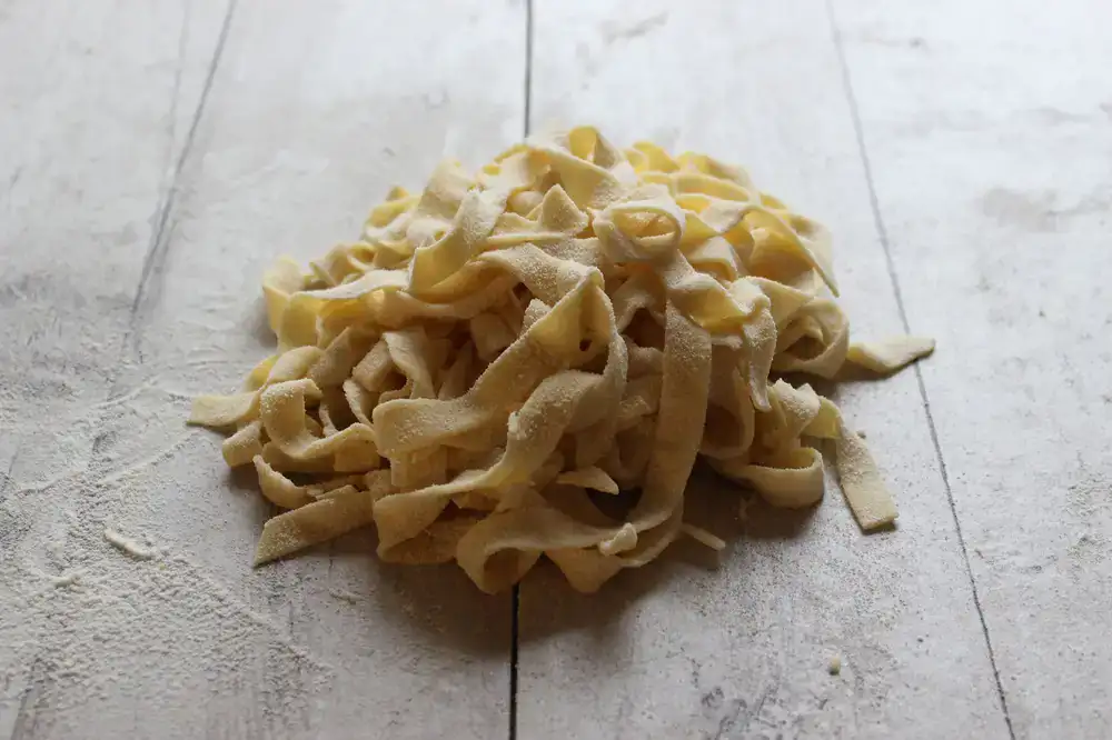 Fresh pasta resting on rustic wooden drying racks inside the shop