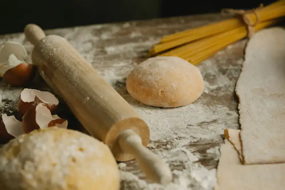 A long rustic wooden table prepared with flour and tools for a pasta making class