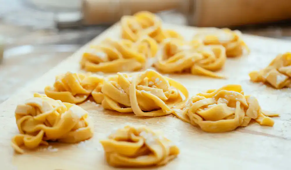 Fresh tagliatelle and farfalle resting on a wooden board