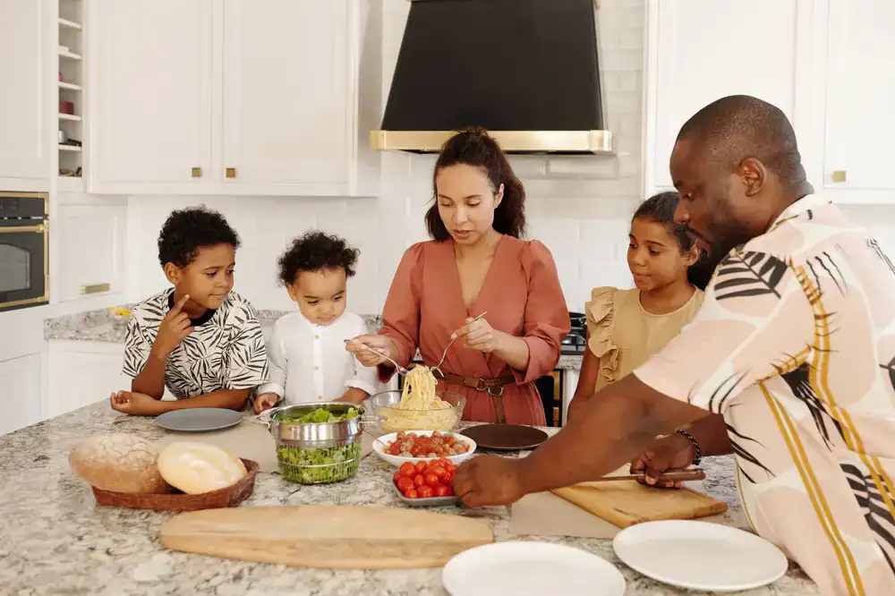 Friends gathering around a kitchen island making fresh pasta